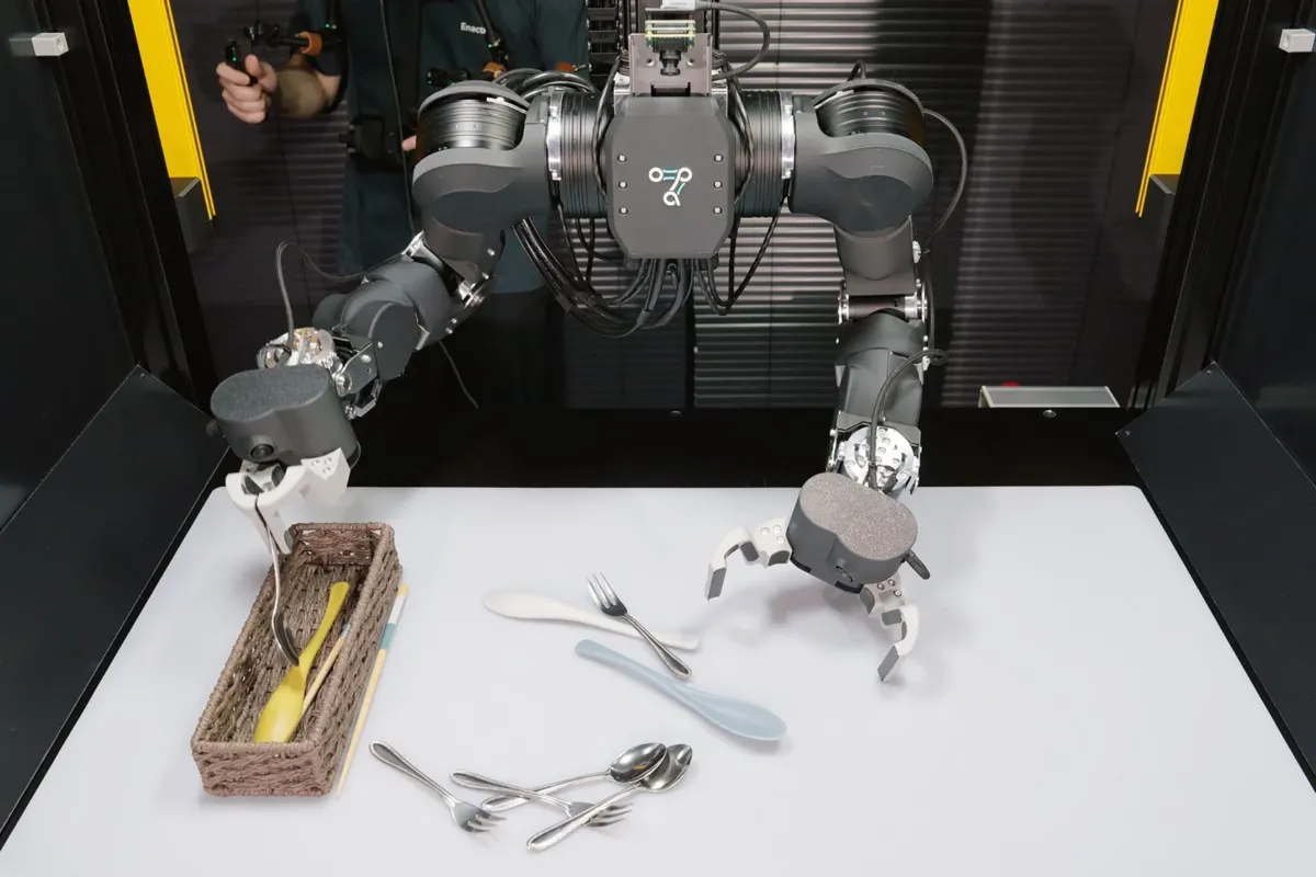 人間がコントローラーで操作する双腕ロボットが、テーブル上の食器を整理している様子